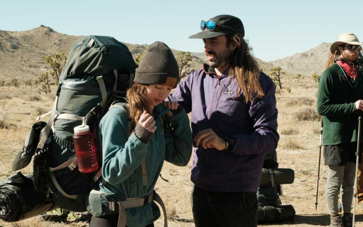 one person helps another adjust their backpacking in Joshua Tree National Park
